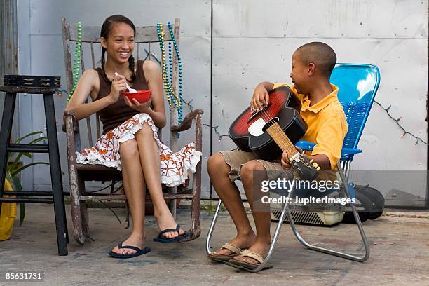 boy playing guitar and teenage girl with bowl - cantare una serenata foto e immagini stock