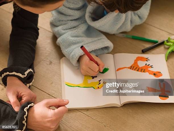 boy drawing dinosaurs with mother - animal drawn stock pictures, royalty-free photos & images