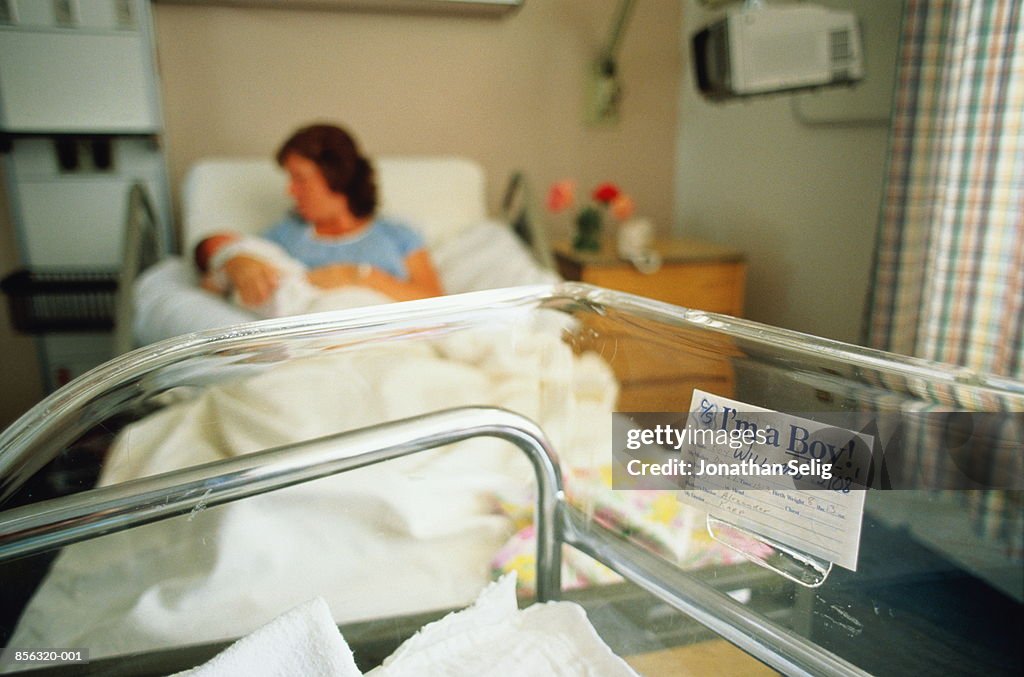 Mother and baby in neonatal maternity ward,cot in fore