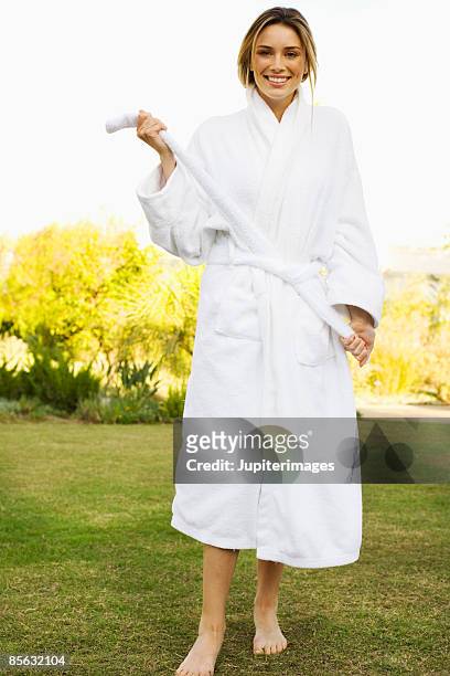 smiling woman tying bathrobe - robe 個照片及圖片檔