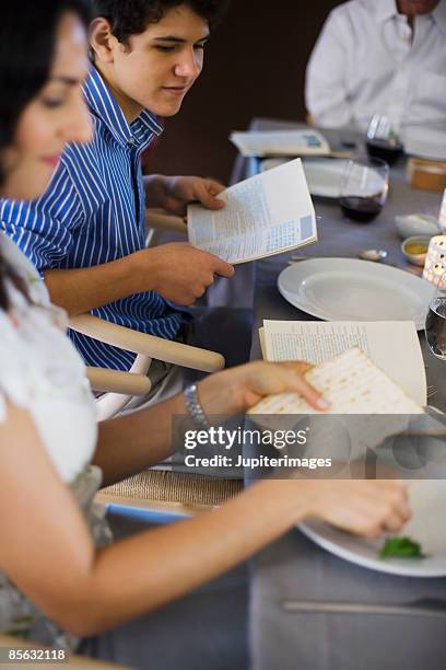 woman eating matzoh and karpas - passover seder stock-fotos und bilder