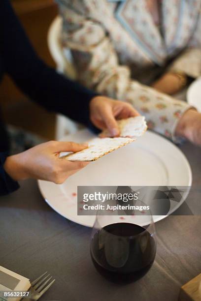 woman breaking matzoh during seder ritual - matzah stock-fotos und bilder