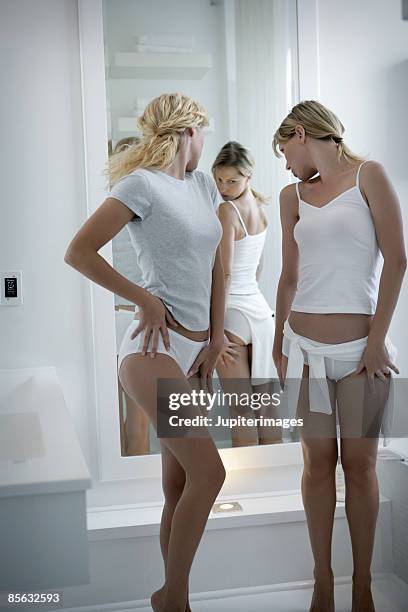 two women looking at themselves critically in the mirror - woman-looking-into-mirror-full-body stock pictures, royalty-free photos & images