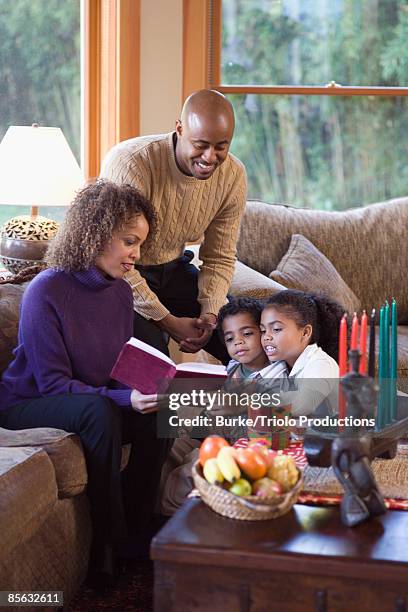 family reading book together during kwanzaa - kinara stock pictures, royalty-free photos & images