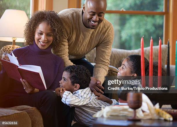 family with book and kwanzaa candles - kwanzaa stock pictures, royalty-free photos & images