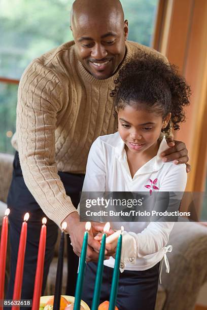 father and daughter lighting candles - kwanzaa celebration stock pictures, royalty-free photos & images