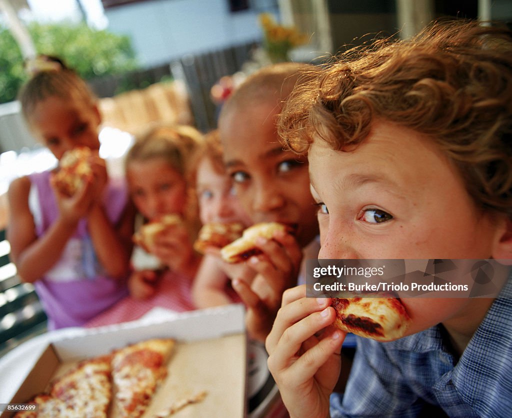 Children eating pizza outdoors
