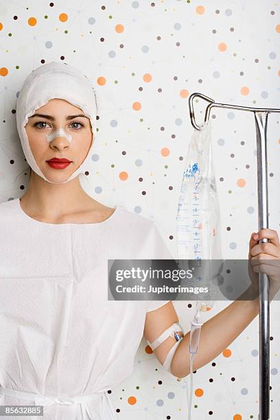 woman with bandaged head wearing hospital gown and iv - plastische chirurgie stockfoto's en -beelden