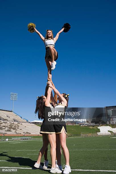 cheerleaders performing stunt - soulever photos et images de collection