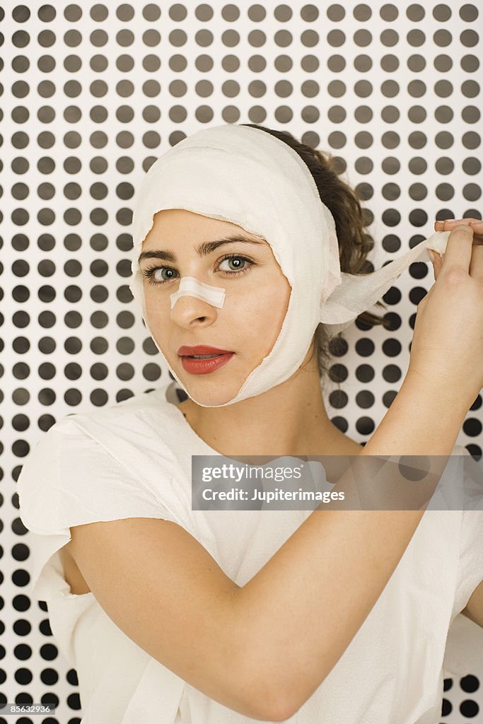 Woman unwrapping bandaged head
