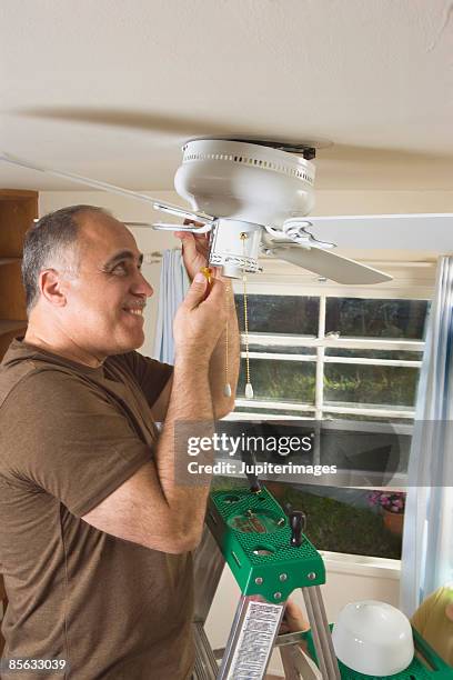 man installing ceiling fan - man installing ceiling fan stock pictures, royalty-free photos & images