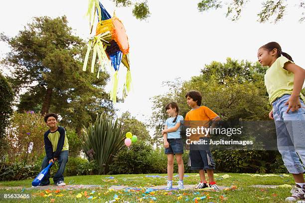 children hitting pinata at birthday party - género humano imagens e fotografias de stock