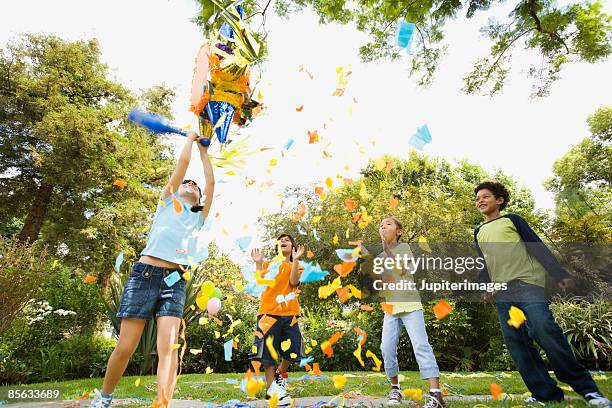 children hitting pinata at birthday party - pinata photos et images de collection