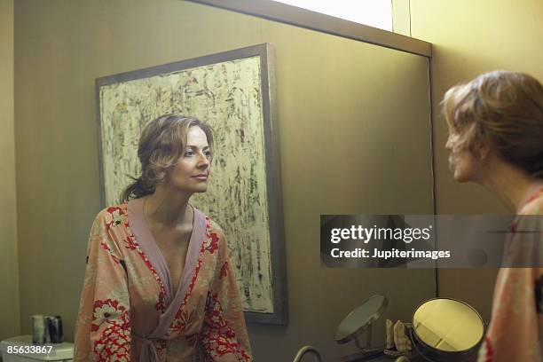 woman looking in mirror - woman in mirror stock pictures, royalty-free photos & images