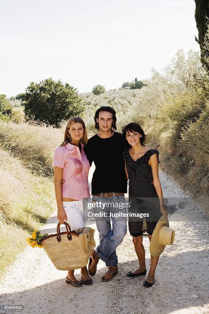 Young adult friends on rural path with basket