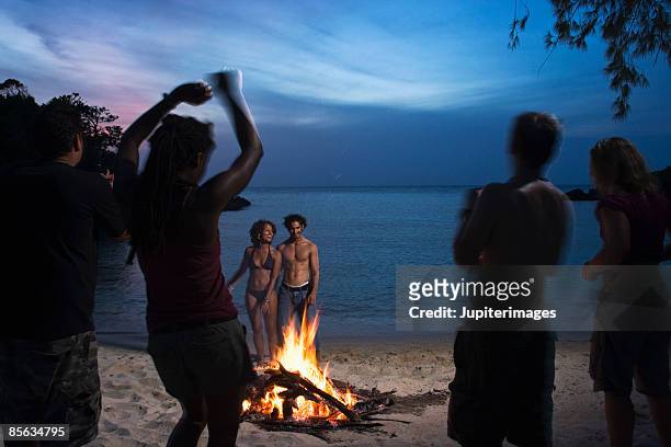people dancing near bonfire on beach - praia noite imagens e fotografias de stock