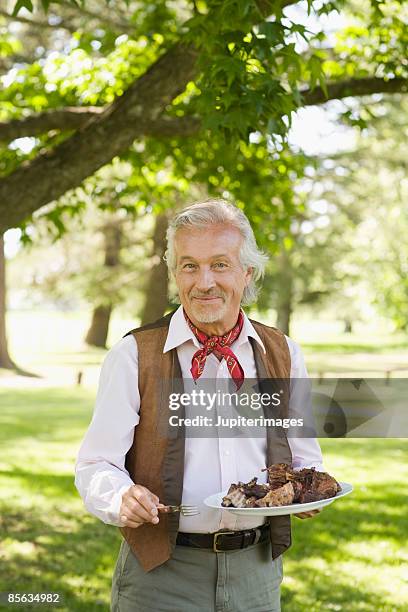 man holding plate of meat - asado stock-fotos und bilder