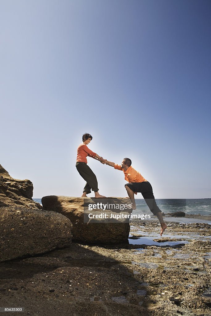 Woman helping man onto rock