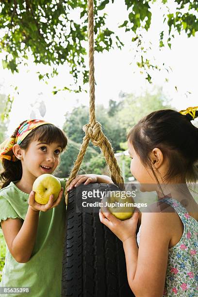 girls with tire swing and apples - tire swing stock pictures, royalty-free photos & images