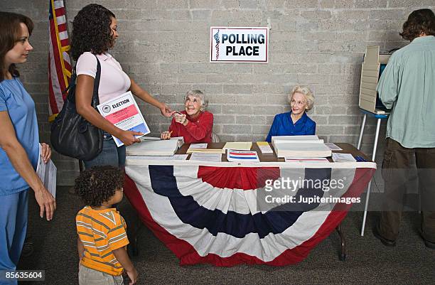 senior women helping voters at polling place - participant fotografías e imágenes de stock