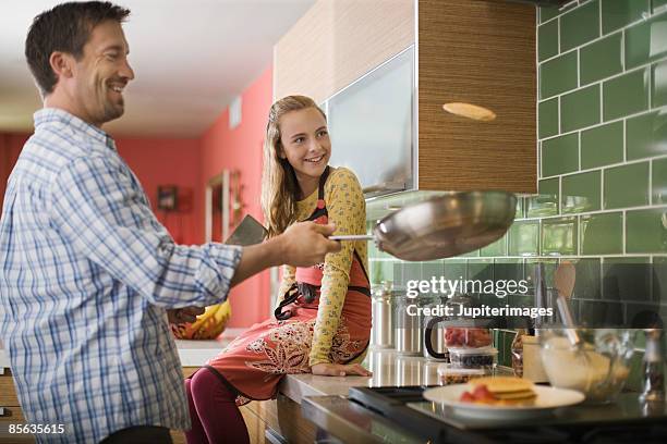 father and daughter flipping pancakes - pancake toss stock-fotos und bilder