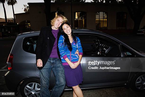 smiling couple with eco-friendly car - auto stehend stock-fotos und bilder