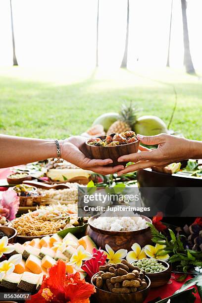 hands passing bowl at hawaiian picnic - hawaiano fotografías e imágenes de stock