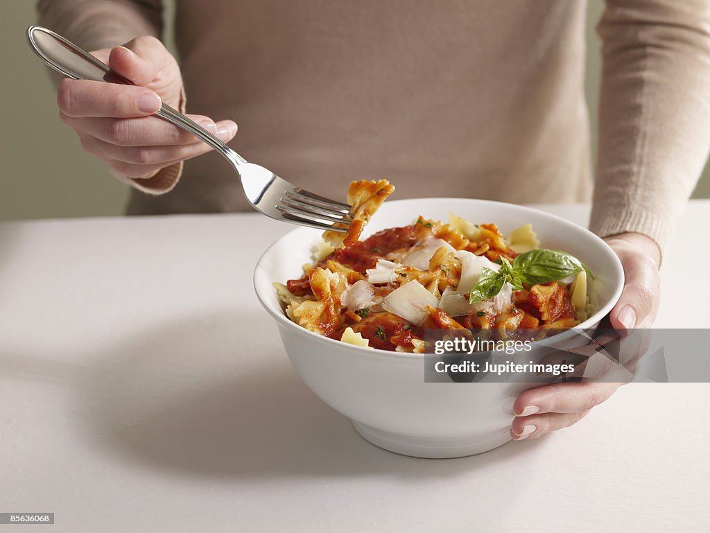 Woman eating bow-tie pasta