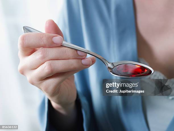 woman's hand with spoonful of cough syrup - spoon in hand ストックフォトと画像