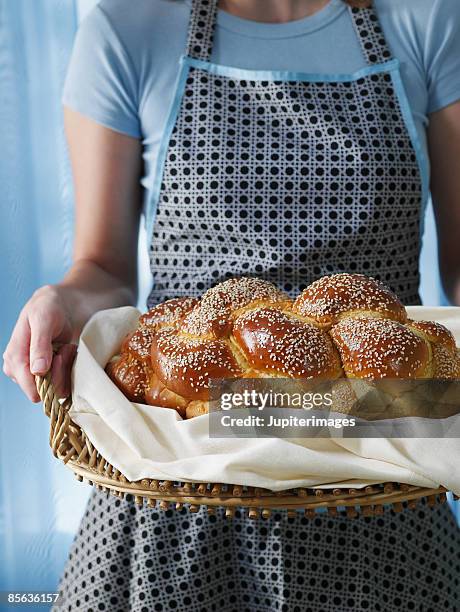 woman holding loaf of sesame challah - jewish sabbath stock pictures, royalty-free photos & images