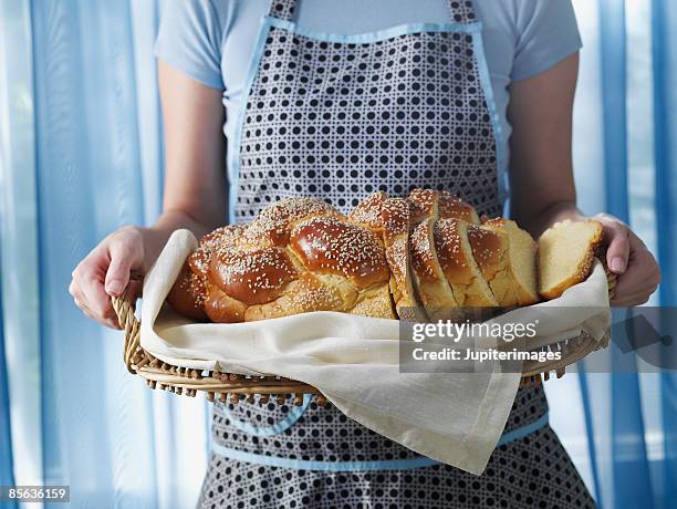 woman holding loaf of sliced challah - challah stock-fotos und bilder