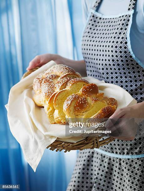 woman holding loaf of sliced challah - jewish sabbath stock pictures, royalty-free photos & images