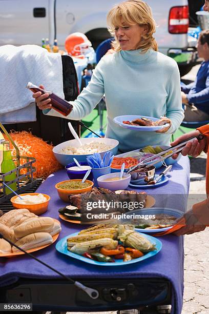 woman with beverage and food at tailgate party - rib food stock pictures, royalty-free photos & images