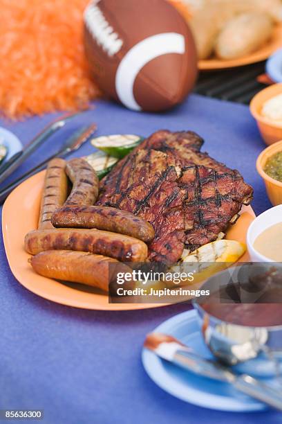 grilled meats and sauce with football on tailgate - tailgating stock pictures, royalty-free photos & images