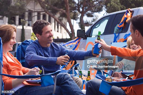 friends passing beer at tailgate party - tailgate stock pictures, royalty-free photos & images