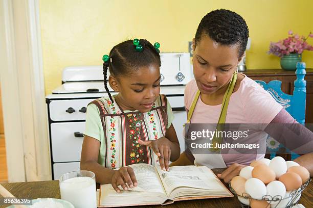 mother and daughter reading recipe - moeder kind zes melk stockfoto's en -beelden