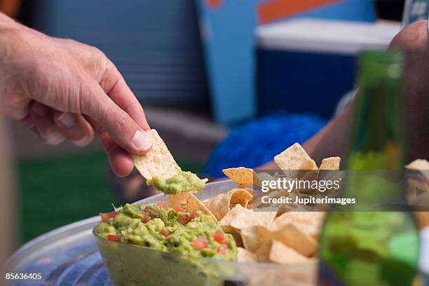 hand with chips and guacamole - guacamole stock pictures, royalty-free photos & images