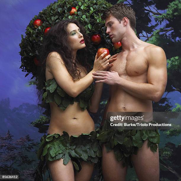 adam and eve holding apple near tree - adam burke stock-fotos und bilder