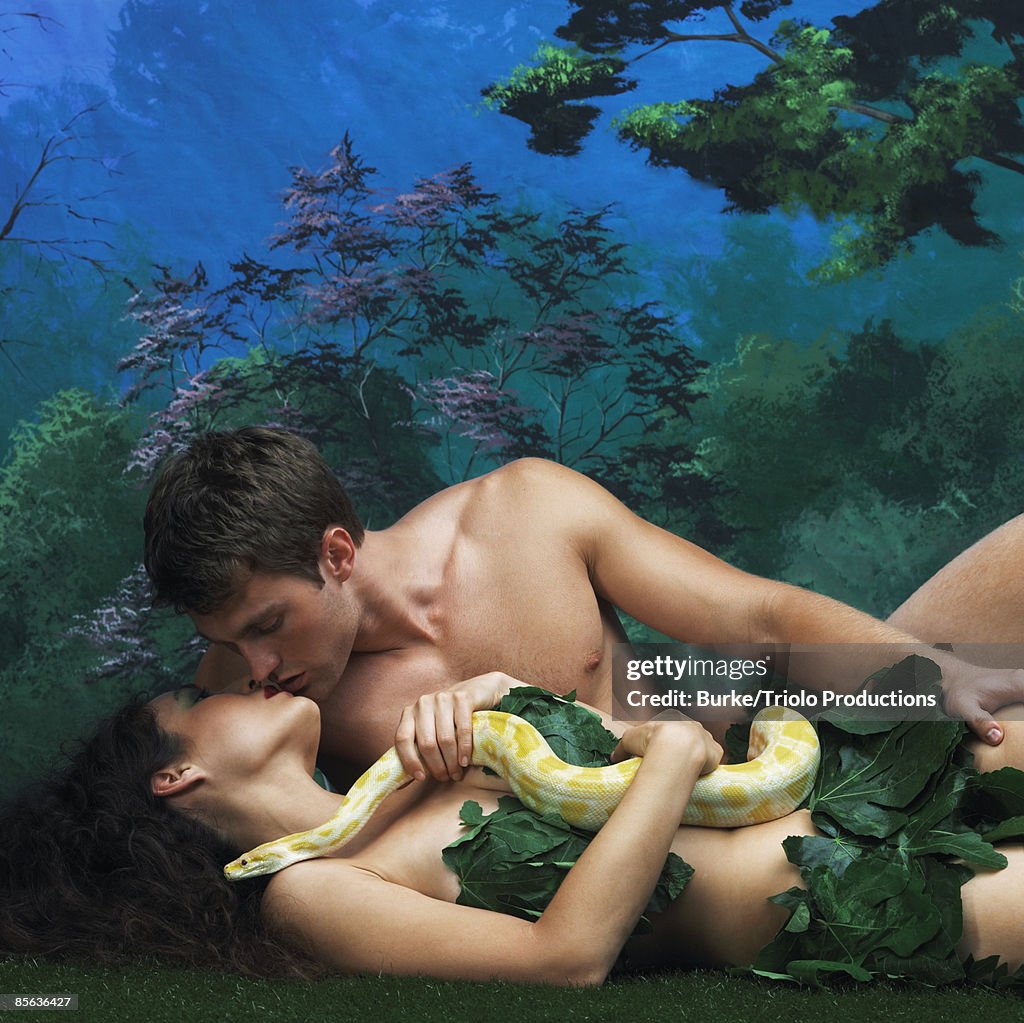 Man and woman kissing and holding snake
