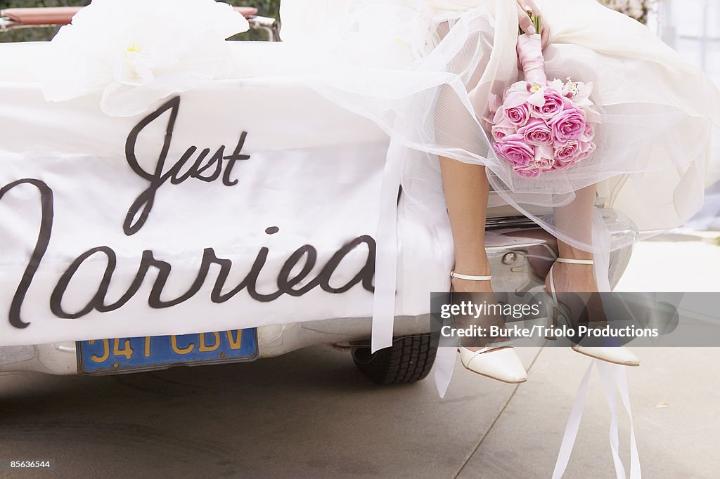 Legs of bride on car with just married sign