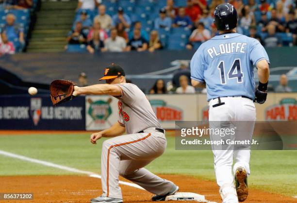 Chris Davis of the Baltimore Orioles make a catch for a force out as Trevor Plouffe of the Tampa Bay Rays runs to first base during the bottom of the...