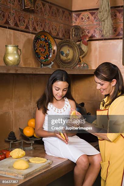 mother and daughter making corn arepas from masa , colombia - arepas stockfoto's en -beelden