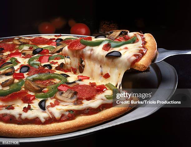 pizza on pan with slice lifted by spatula - pizza imagens e fotografias de stock