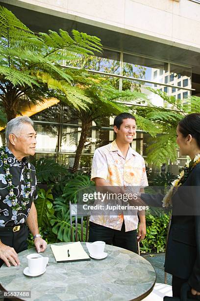 men shaking hands with businesswoman outdoors - hawaii hemd stock-fotos und bilder