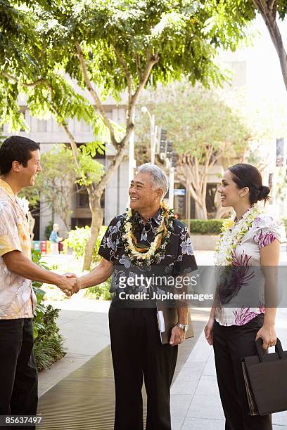 businesspeople shaking hands in hawaii - lei day hawaii stock-fotos und bilder