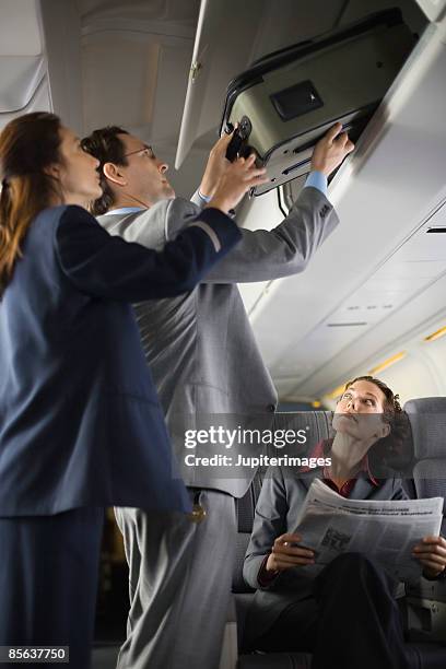 stewardess assisting passenger with luggage - hostess foto e immagini stock