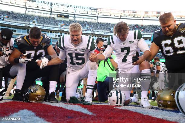 Josh McCown and Chandler Catanzaro of the New York Jets pray with Josh Wells and Tyler Shatley of the Jacksonville Jaguars aftertheir game at MetLife...