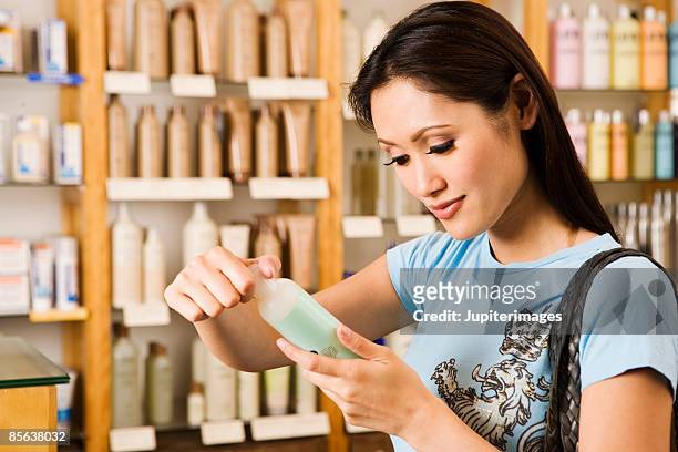 woman looking at beauty product - cosmetic testing store stock pictures, royalty-free photos & images