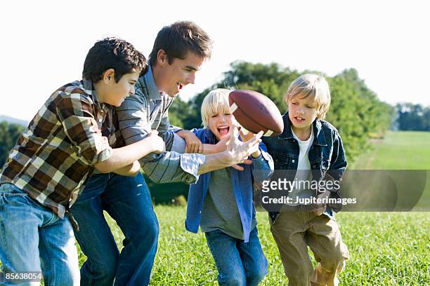 father and sons playing football - tackle american football player stockfoto's en -beelden