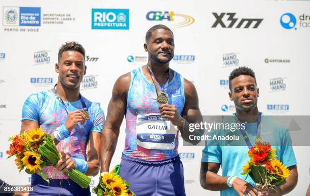 Athletes Justin Gatlin of the US, Paulo Andre de Oliveira of Brazil and Isiah Young of the US pose on the podium after the men's 100m final of the...